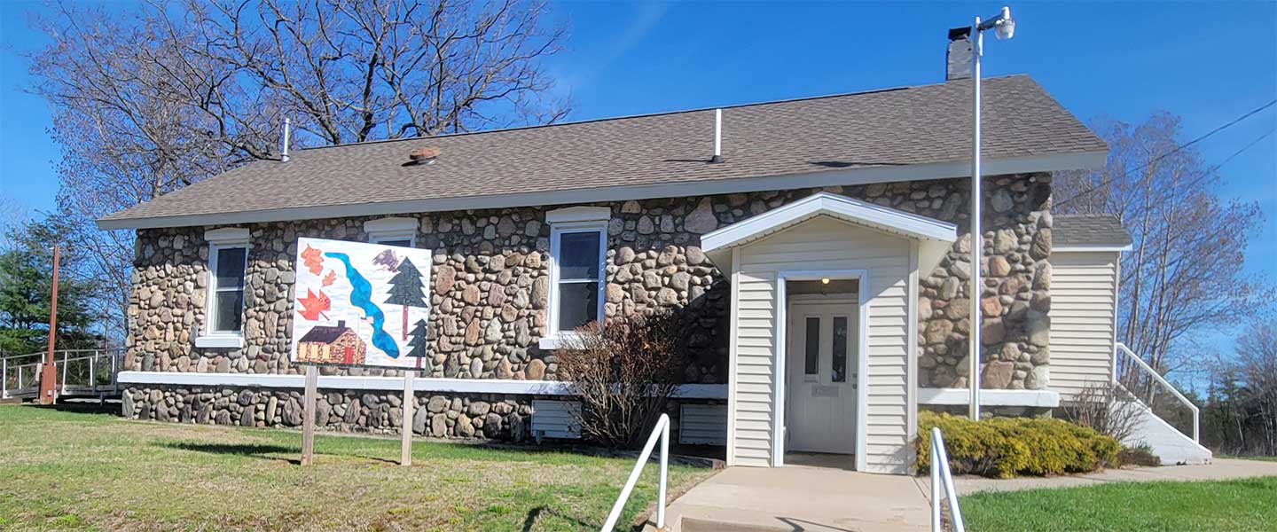 Frost Township Hall stone building with American flag and township sign, Harrison, Michigan